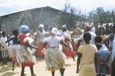 Bolossoville, Gabon, June 1992. Colorful and exuberant ceremonies mark important events and holidays: weddings, funerals, and political events are often cause for traditional dances. This photo gives an idea of what it's like, but the drums and singing are not caught on film. It's really an experience to be there in person.  Photo by Andrew Wickens.